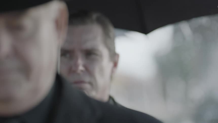 A funeral procession mourns in the rain