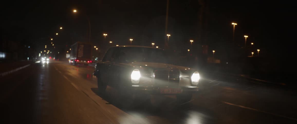 A car driving at night during the rain with headlights on as a tractor trailer passes the other direction