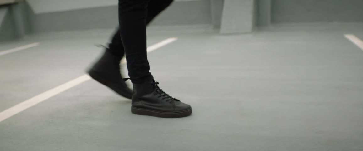Foot of a young man wearing black walking on the roof of a parking garage
