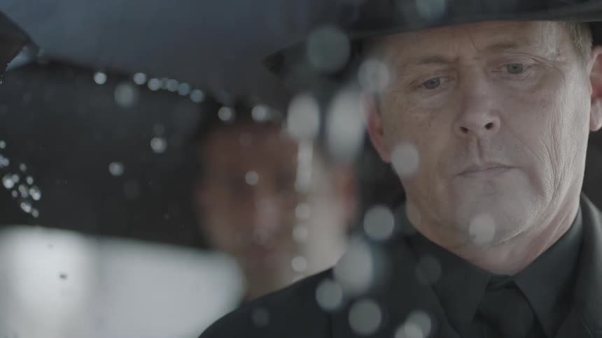 Rain falls around a man with an umbrella