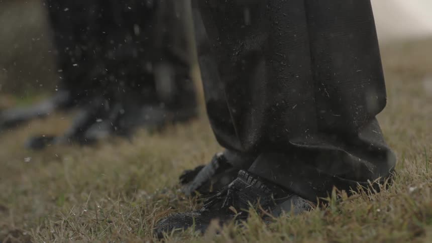 People stand in the grass in the rain