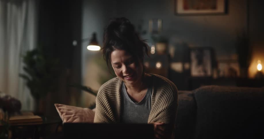 Happy woman emotionally talks on a video call through her laptop in the living room at home