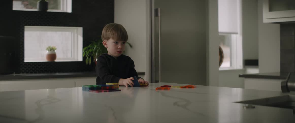A boy plays with building blocks at the kitchen counter