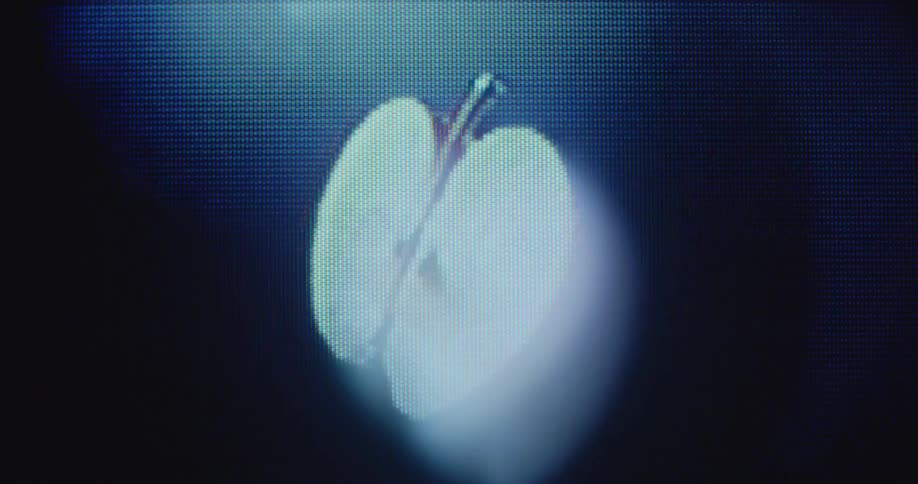 CGI pixelated red apple slice spins around with black background on old television screen with transformation