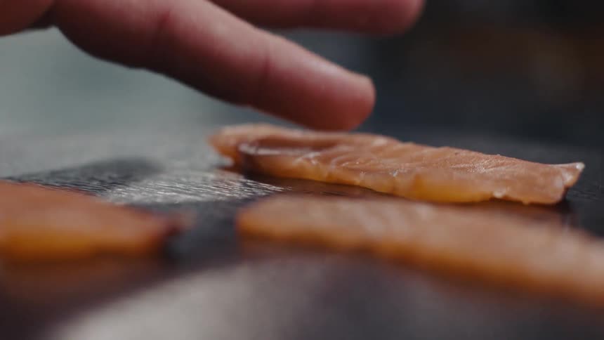 A person plating sliced fish