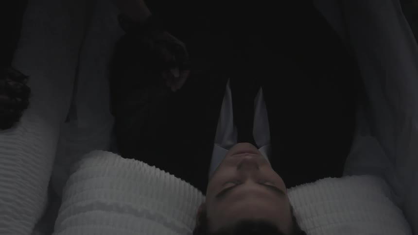 A person touches a corpse in a casket