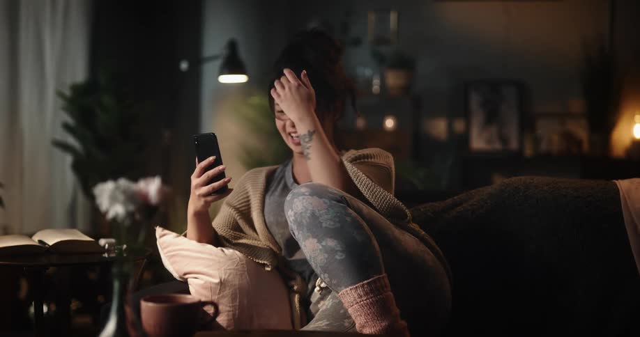 Woman sits on couch having a video call via smartphone