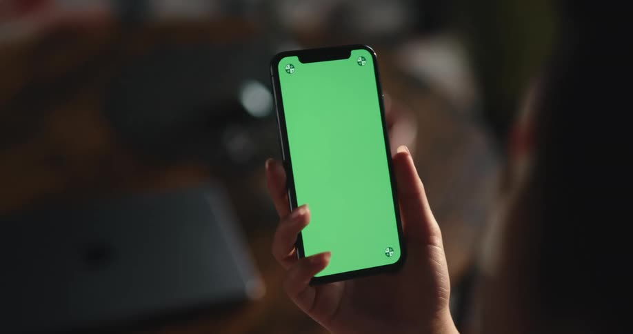 Young woman looking at iphone with replaceable green screen