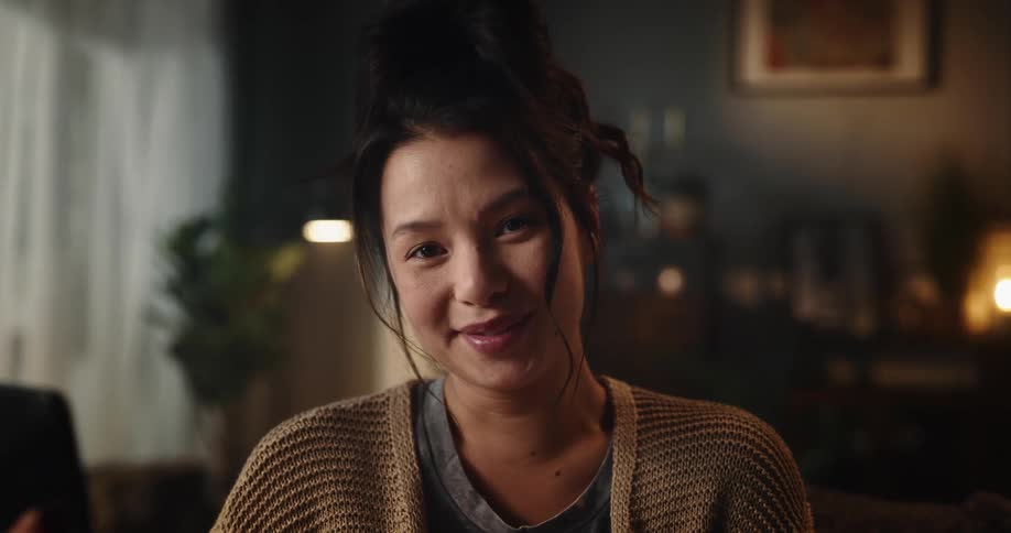 A womans face smiling while she looks at and holds her cell phone in her hand