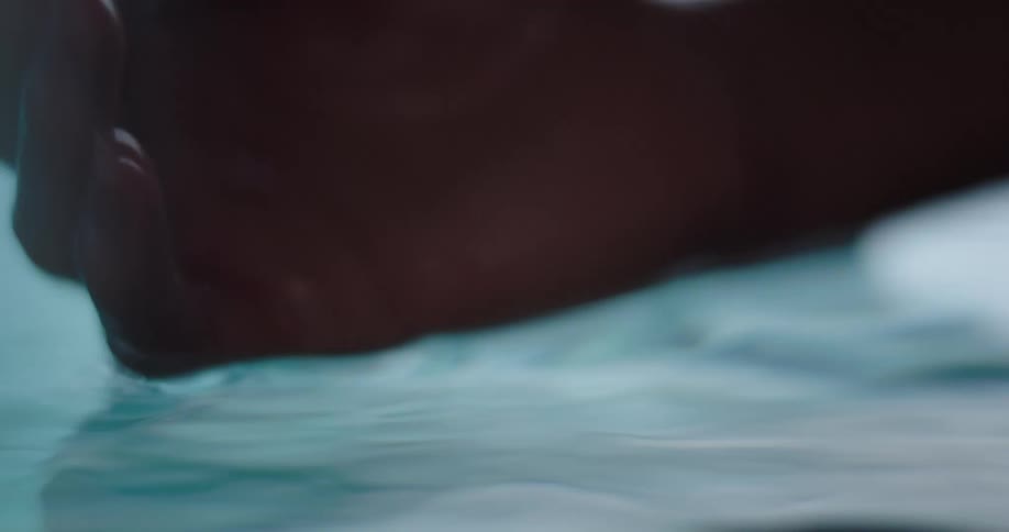 A persons hand emerging from underwater creating ripples in the water