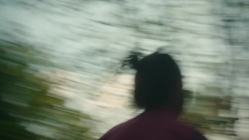 Woman with pink jacket and black leggings jogs in the green forest at sunset