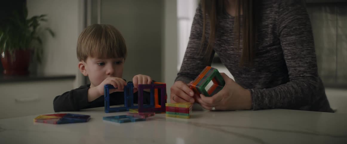 Mother leans forward as she and son build with squares