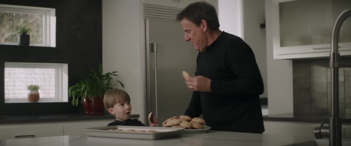 Grandfather and grandson eating homemade cookies in the kitchen