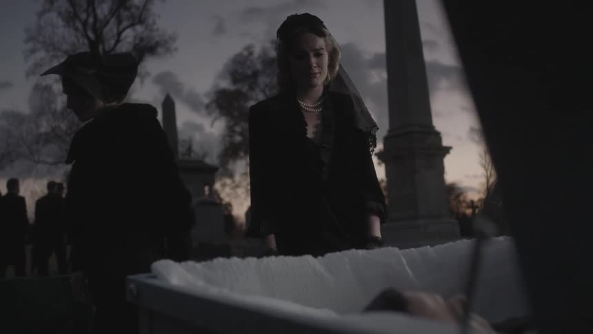 People get up to leave as a woman approaches a casket at a funeral