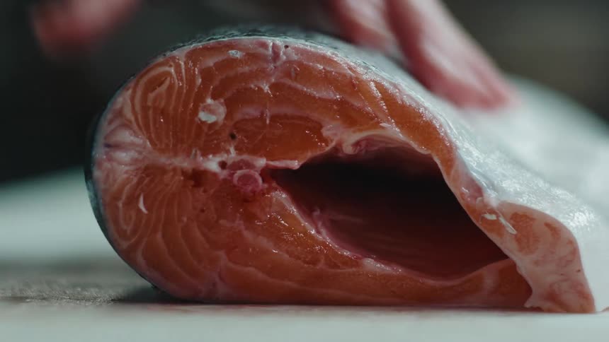 A man removes the cut head from a salmon