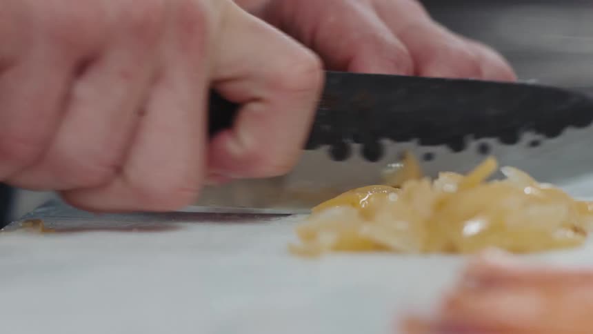 Close up of the hands of a chef using a sharp kitchen knife to chop vegetables