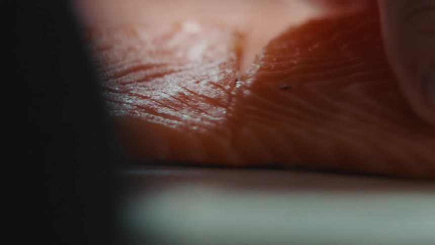 A man cuts a salmon filet into smaller pieces