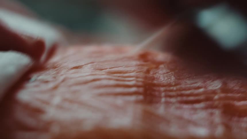 Close up of a chef using a pair of pliers to remove fishbones from salmon