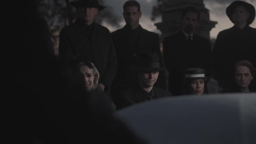Mourners gather in a cemetery for a funeral