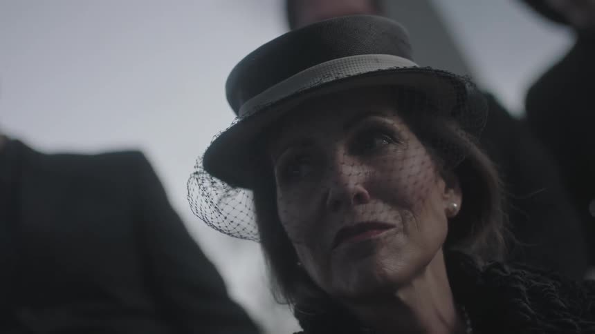 A mourning woman wears a hat and veil