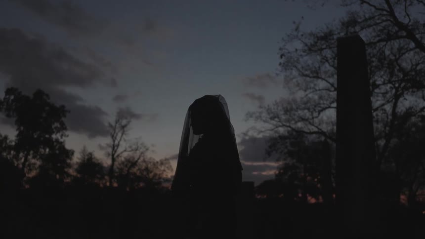 A veiled woman walks outside at dawn