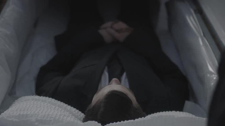 A dead man lies in a coffin