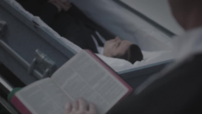 A priest reads from a bible at a funeral