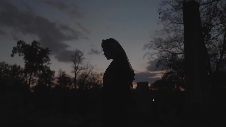 Silhouette of a woman standing still outside at sunset