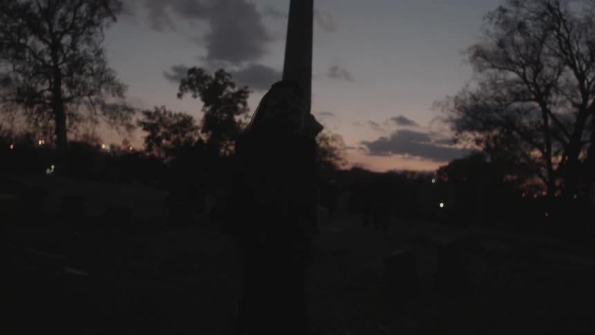 A woman walking in a cemetery at sunset