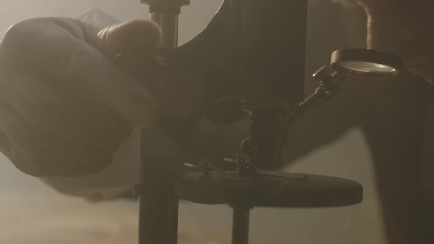 A man adjusts a microscope