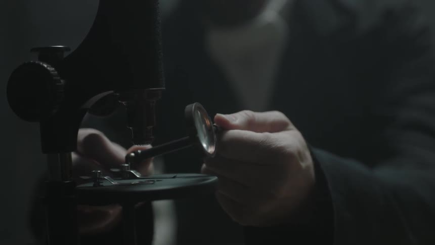 A man adjusts a microscope