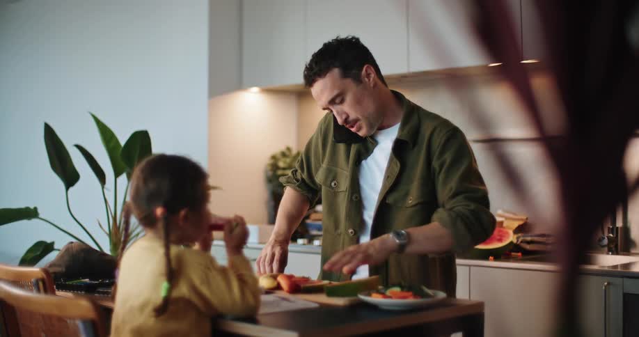 A man talks on his phone while eating with his child