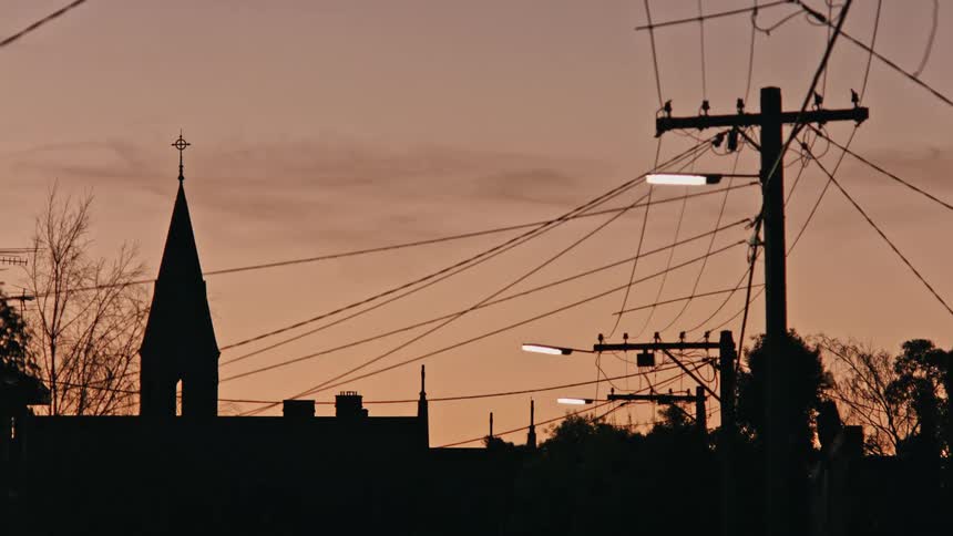Silhouette of a church tower on the skyline of a small town at evening