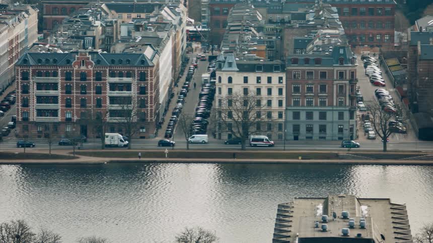 Traffic moves along road between water and apartment buildings