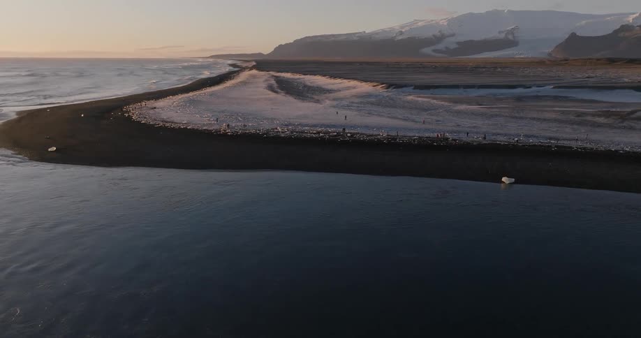 An aerial view of a snowy coastline at sunrise
