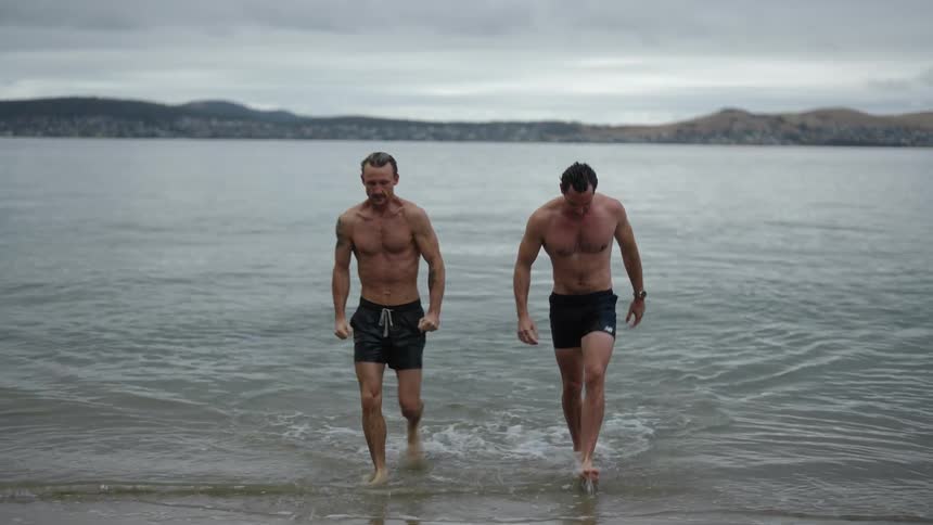 Two men are walking on the beach together