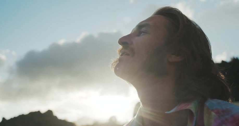 Man stands with his head back enjoying sunshine
