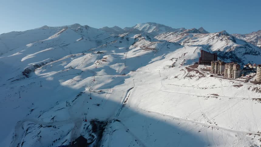 An aerial of snow covered mountain ranges with buildings in a small town on the hillside