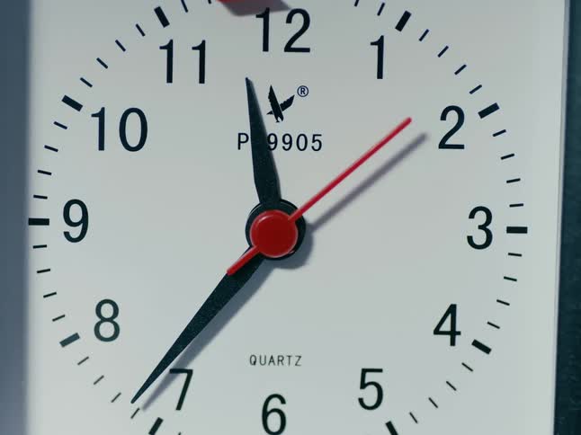 A close up of a clock with black minute and hour hands and a red second hand
