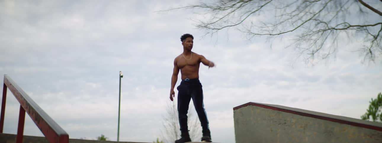 Young muscular shirtless man wearing roller skates slides down a ramp near stairs