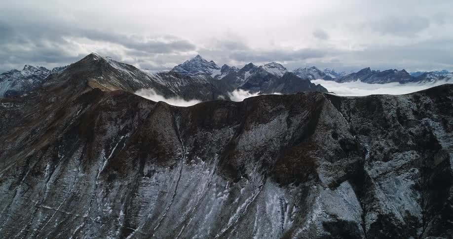 A mountain ridge covered in light snow on a cloudy day