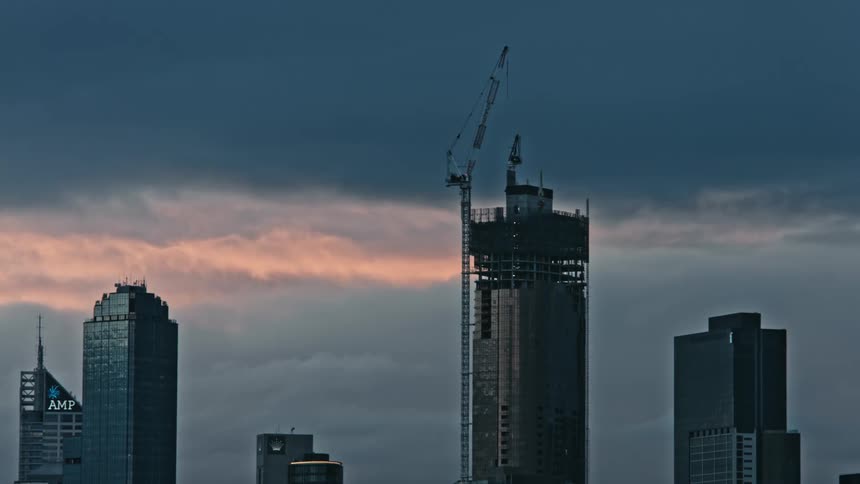 The top of tall buildings one being built with a construction crane on the side