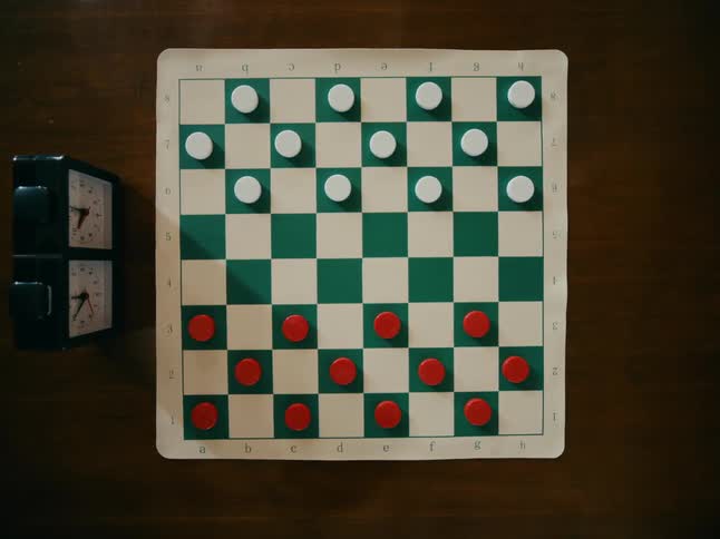 A checkerboard game is set up on a table with a timer clock