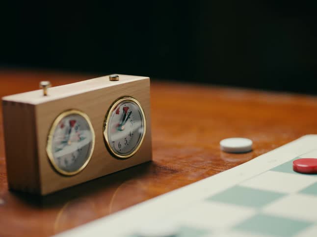 A close up of a game clock as a person pushes it down with their finger