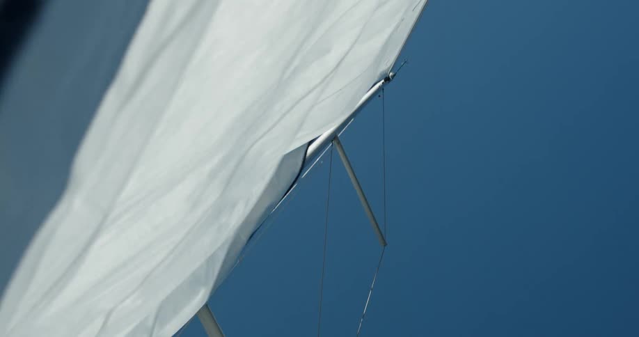 The wind blows the sail of a sailboat on a mast