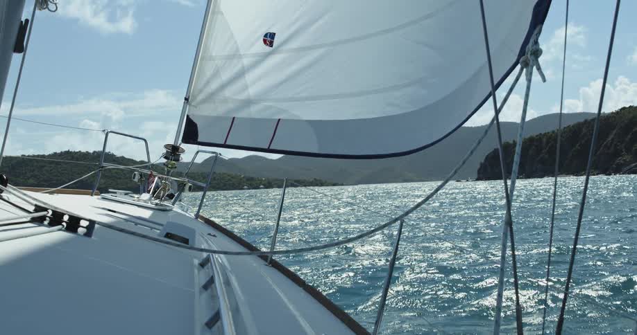 A boat sailing on wavey waters with mountains on either side and ahead