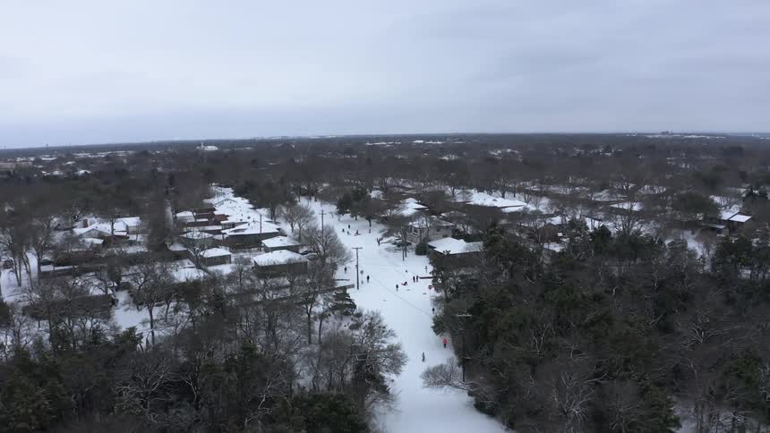 Aerial of snow covered neighborhood with people walking around