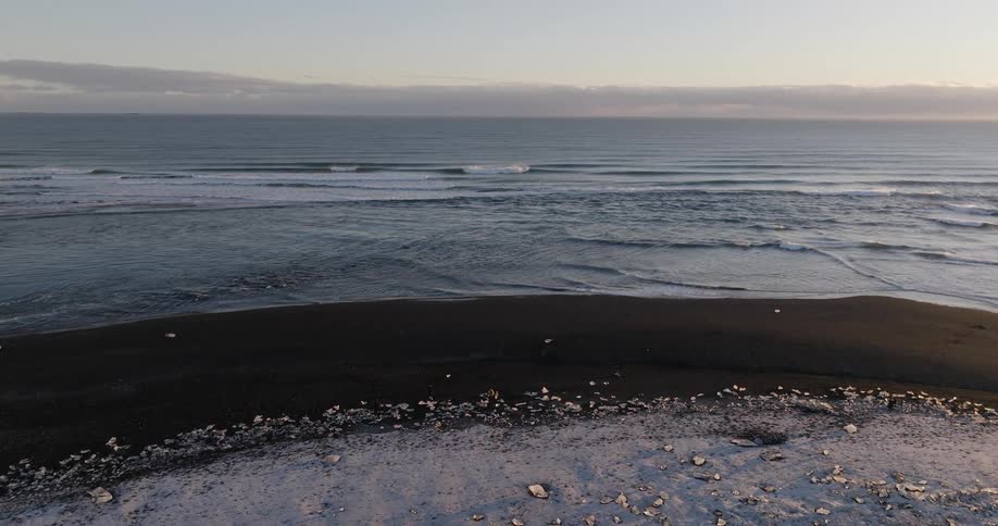 Aerial view of gentle ocean waves crashing in the coast at evening