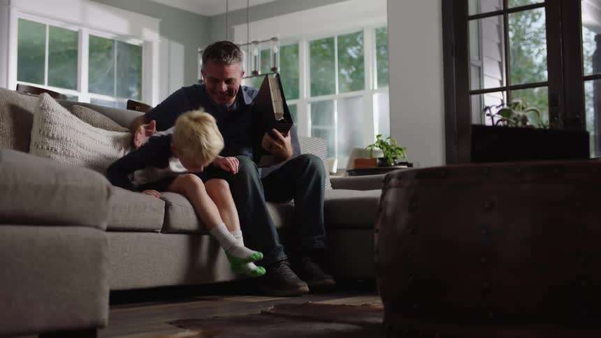 Grandfather and grandson view photo album in living room before leaving