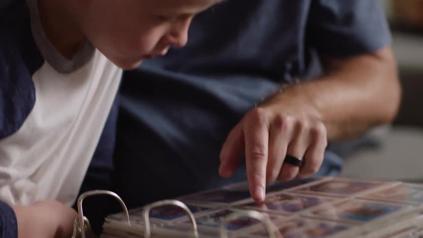 A grandfather shows his grandson baseball cards in a binder